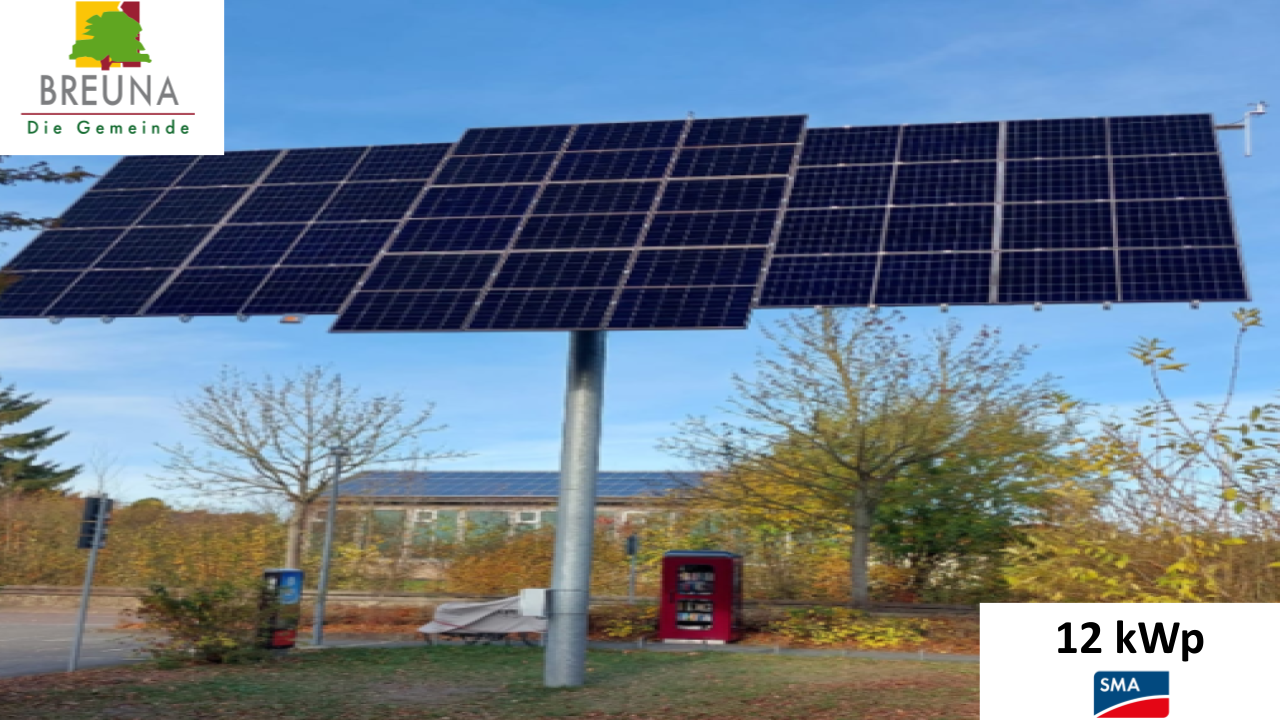 Eine große Solaranlage mit dunklen Modulen steht auf einem Mast vor herbstlichen Bäumen