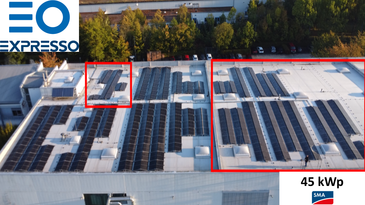 Ein großes weißes Flachdach mit vielen schwarzen Solarpaneelen und vereinzelten Lichtkuppeln