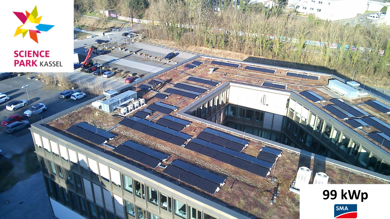 Dach eines modernen Gebäudes mit vielen Solarpanelen und begrünten Flächen bei Sonne