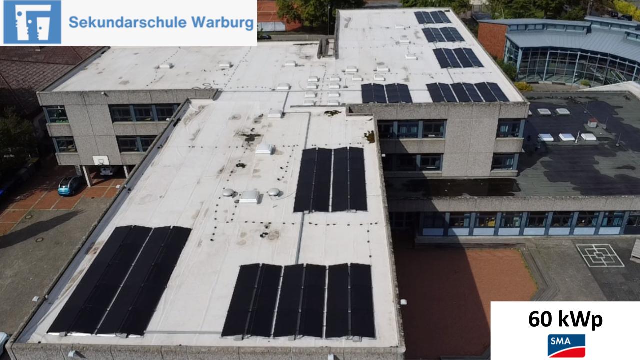 Dach einer Schule in Warburg mit vielen schwarzen Solarpanels auf weißer Fläche