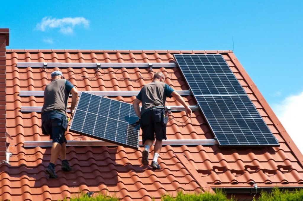 Handwerker brinen eine Photovoltaik-Anlage am Haus an